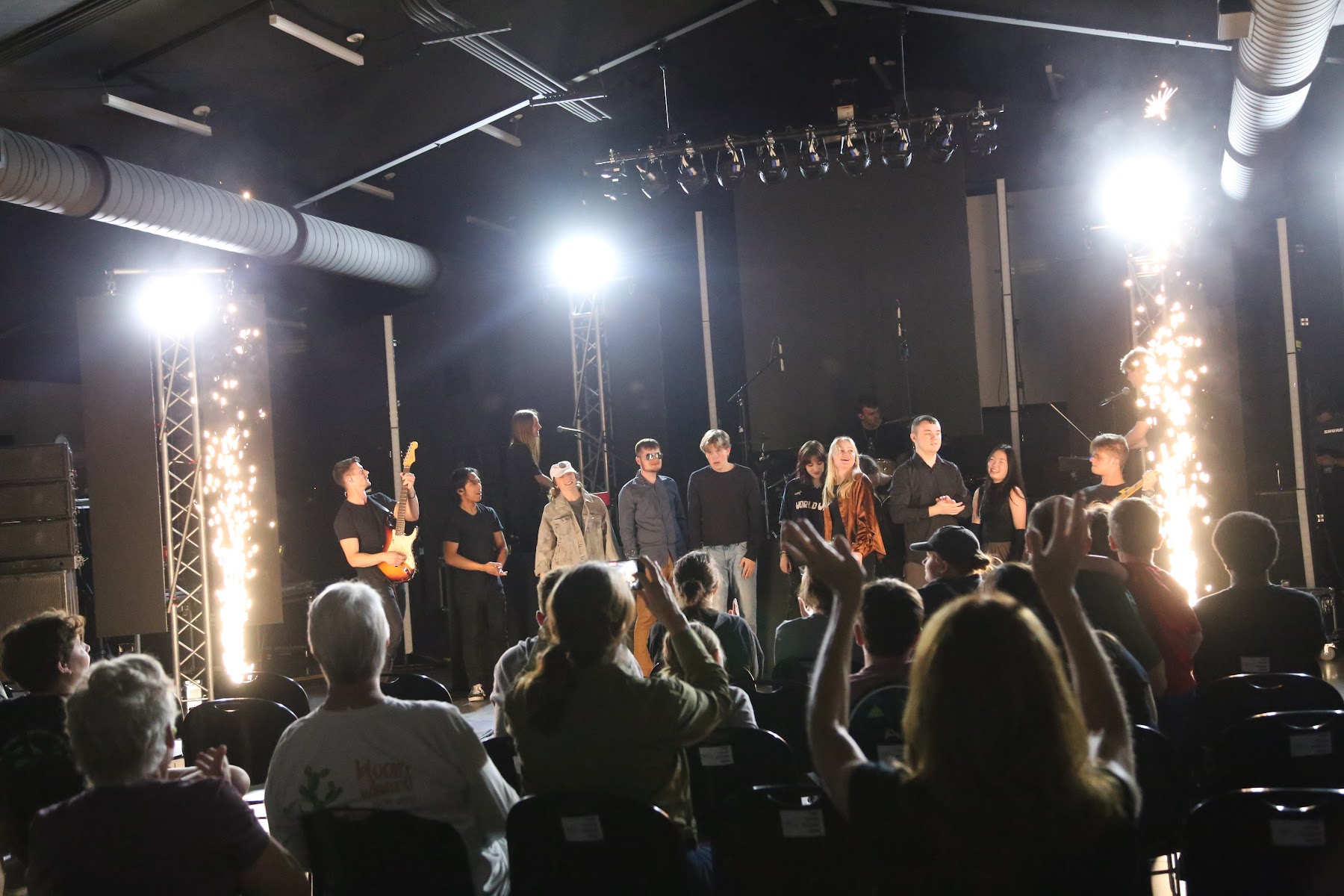 Students on stage in front of a crowd with sparks